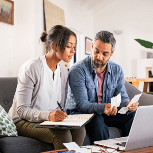 Couple using laptop and notebook to plan financial decisions