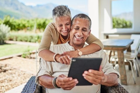 Happy couple, reviewing information on tablet
