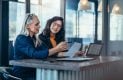Two women analyzing documents at office