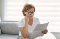 retired woman checking bill on sofa