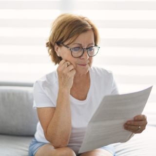 retired woman checking bill on sofa