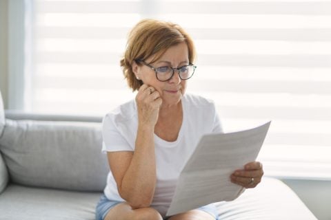 retired woman checking bill on sofa