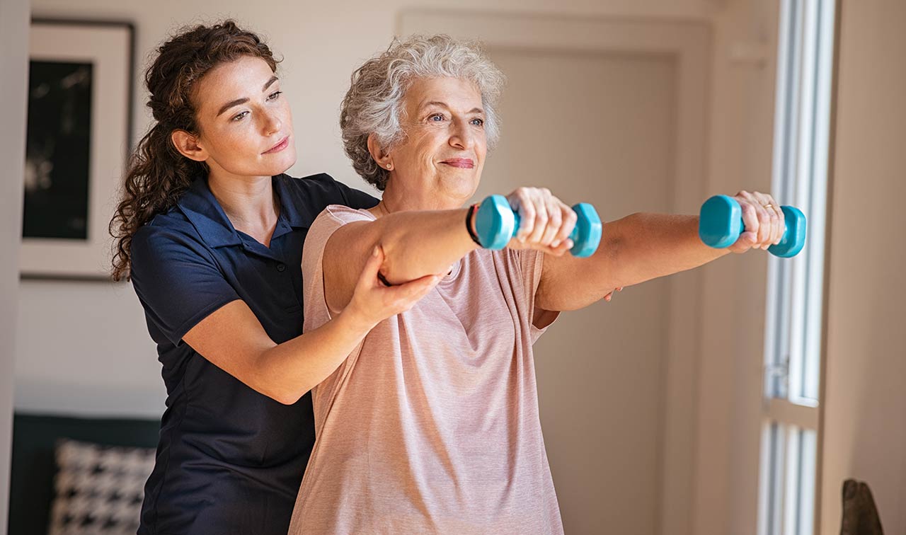 A physical therapist helping elderly woman with daily strengthening exercises