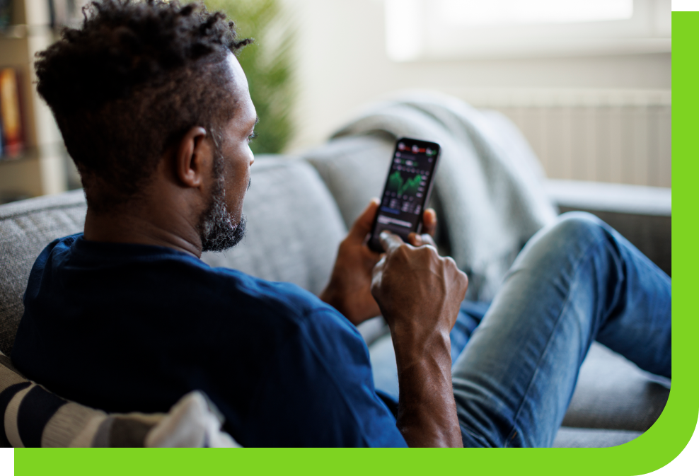 Adult man sitting on a couch looking at phone, reading financial statistics