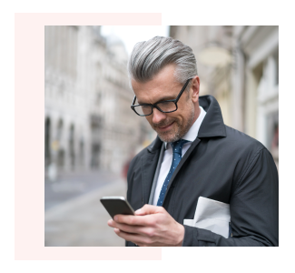 Middle aged man looking at cell phone while waiting on the street