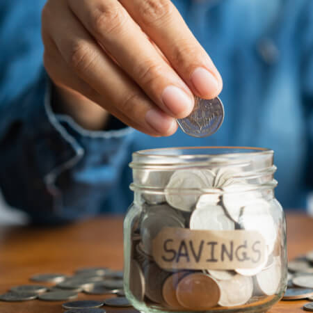 The woman hand is putting a coin in a glass bottle and saving money for future