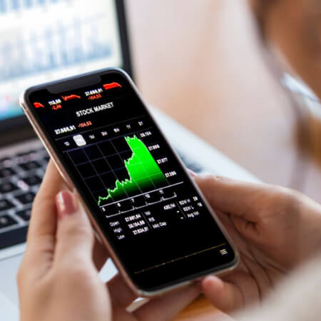 Young finance expert analyzing financial charts on smart phone